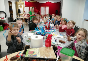 Dzieci przy stole pokazują swoje wykonane renifery